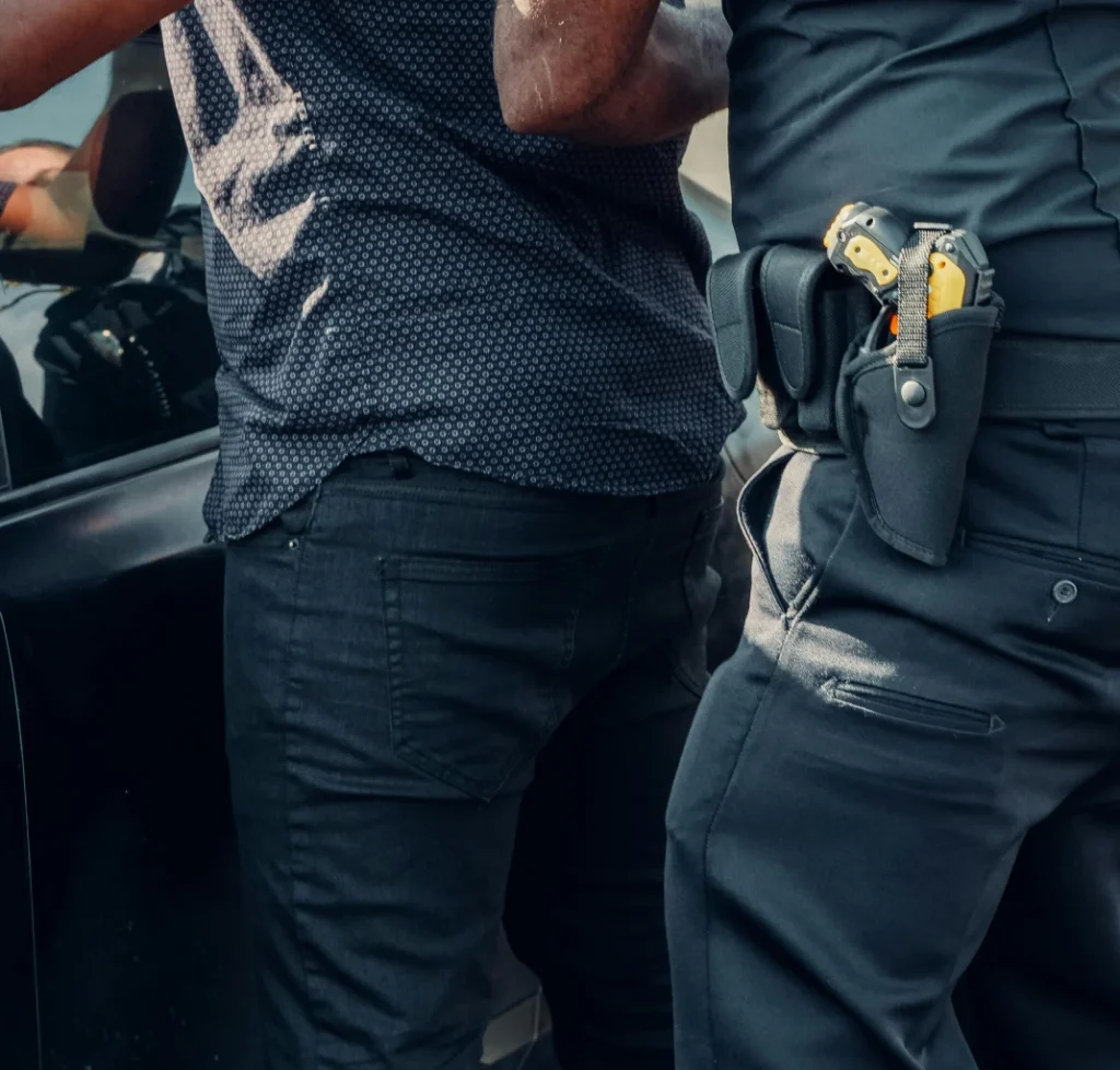Police officer with holstered handcuffs and taser, representing a drug possession arrest