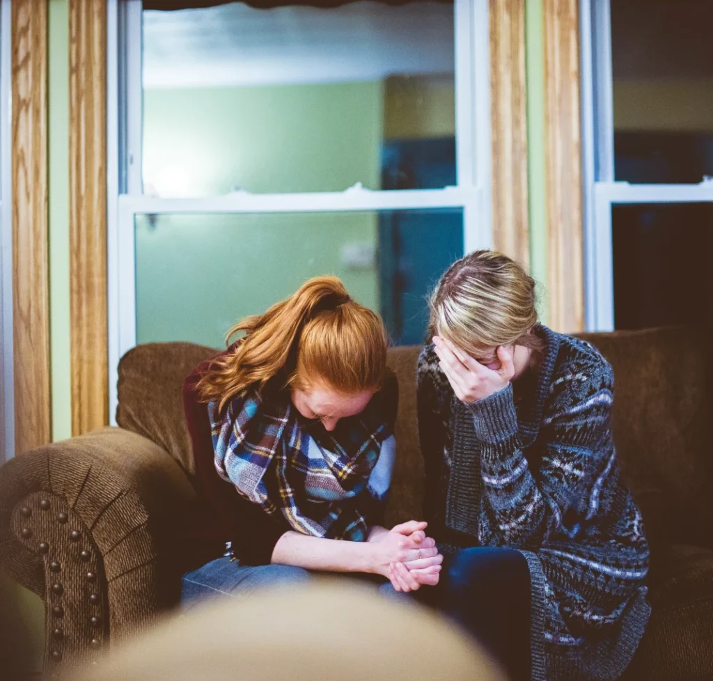 Two women comforting each other on a couch, representing an assault causes bodily injury - family violence charge